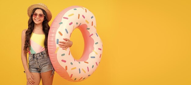 Summer child happy beach kid in straw hat and sunglasses with doughnut inflatable ring summer vacation Banner of summer child girl in swimsuit studio poster header with copy space