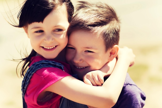 summer, childhood, family, friendship and people concept - two happy kids hugging outdoors