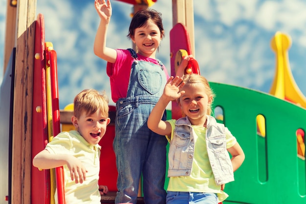 summer, childhood, leisure, friendship and people concept - group of happy kids waving hands on children playground