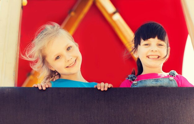 summer, childhood, leisure, friendship and people concept - group of happy little girls on children playground climbing frame