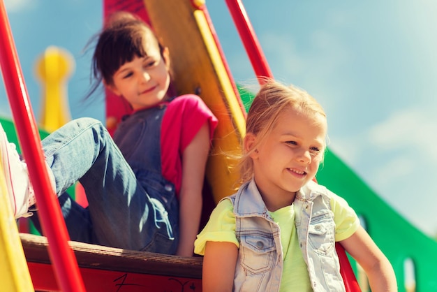 summer, childhood, leisure, friendship and people concept - happy kids on children playground climbing frame