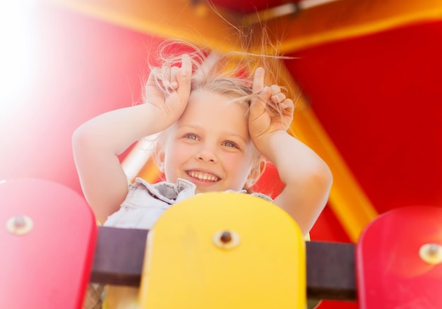 Concetto di estate, infanzia, tempo libero e persone - bambina felice sul telaio da arrampicata per parco giochi
