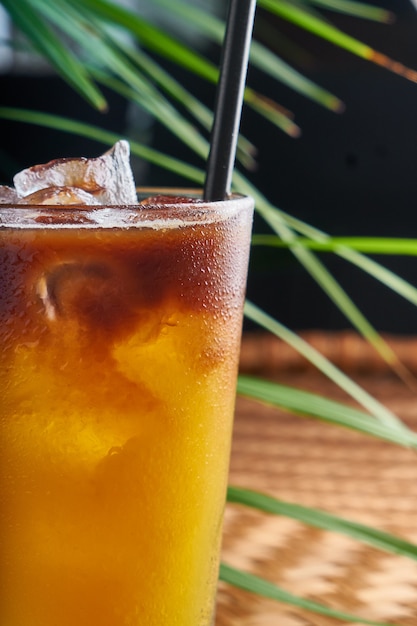 Летние охлажденные напитки со свежевыжатым соком на плетеном столе с листьями
