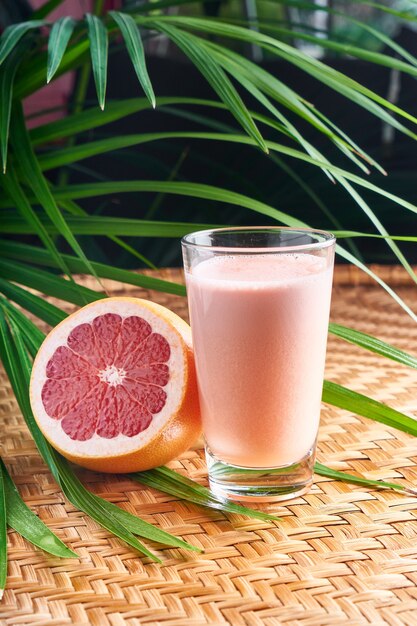 Summer chilled drinks with fresh pink juice with half fruit on wicker basket with leaves