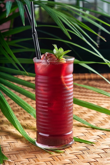 Summer chilled drinks with fresh raspberry juice and hibiscus on wicker table with leaves