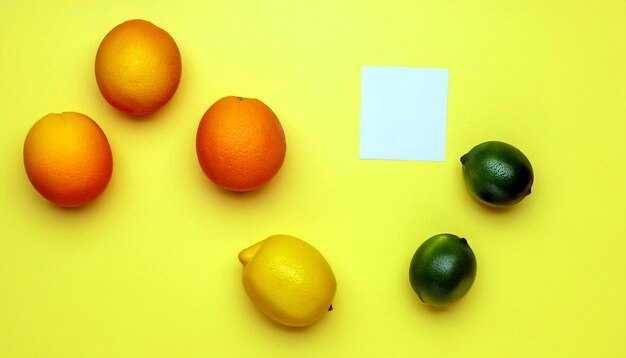 パステルイエローの背景に夏の柑橘類の喜びオレンジレモンとライム新鮮なフルーツのミニマリズム
