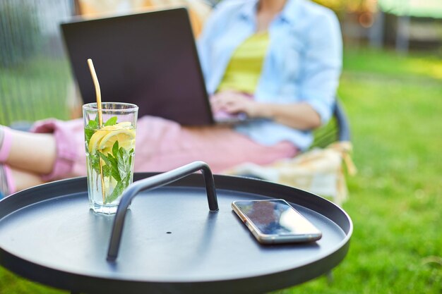 Summer citrus lemonade with reusable metal straws Woman using typing