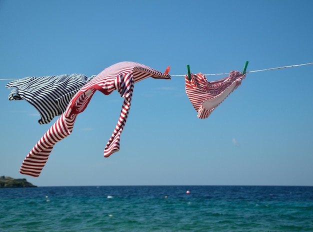 summer clothes of navy look on drying wire with sea in background
