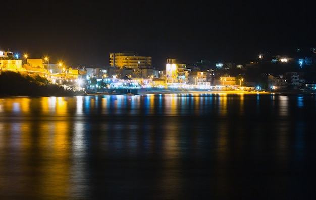 Vista notturna della costa estiva con la città illuminata di himare (albania)