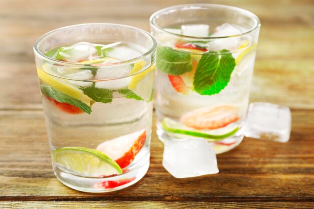 Summer cocktail with ice cubes on wooden table