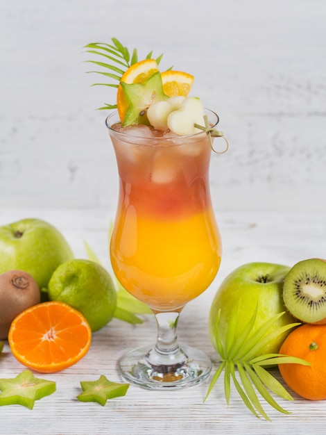 Летний коктейль с различными тропическими фруктами вокруг