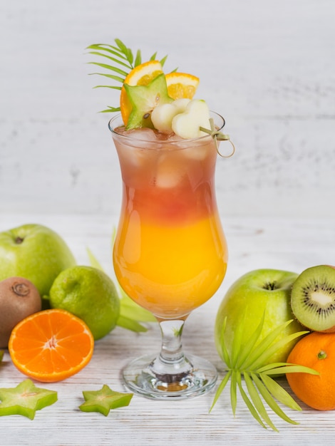 Summer cocktail with various tropical fruits around