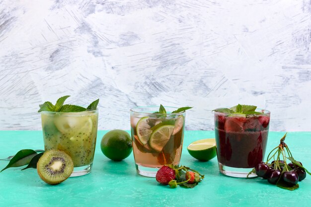 Summer cold drinks with fresh fruits, berries and mint. Strawberry mojito, cherry smoothies, cocktail of kiwi in glasses .