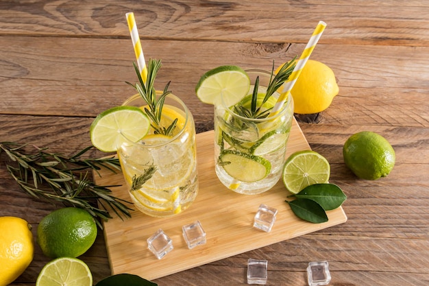 Bevande fredde estive con agrumi a fette e acqua frizzante in due bicchieri su un tavolo di legno in stile rustico