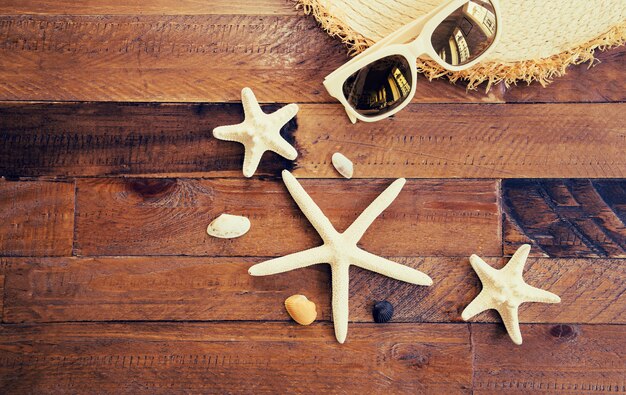 Foto composizione estiva con accessori e stelle marine e conchiglie sul tavolo di legno