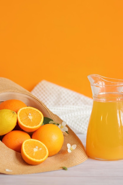 デカンタに入った柑橘系の果物とジュースの夏の組成物夏の帽子の中の熟したオレンジ