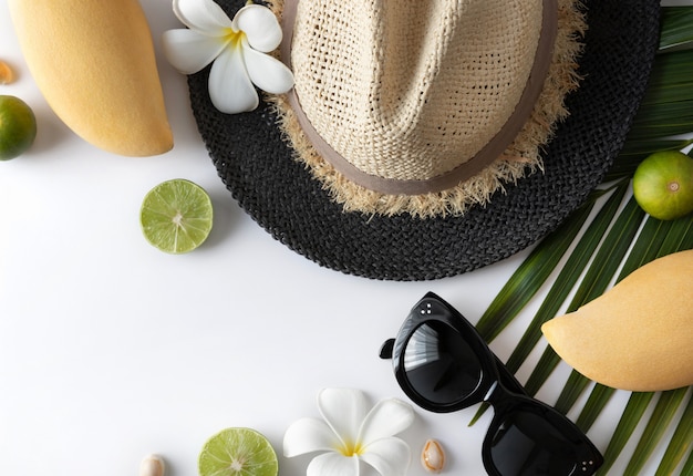 Summer composition with fruits, hat, tropical palm leaf and flowers on white background