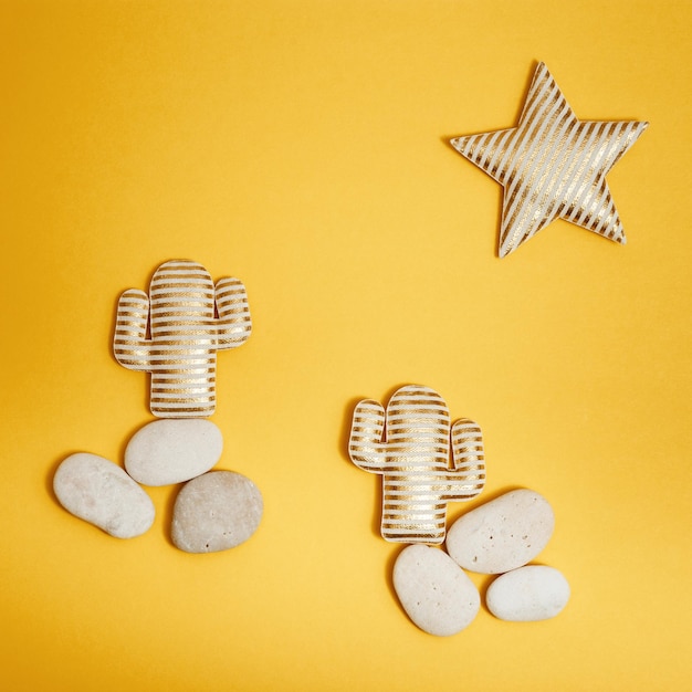 Summer composition with two golden striped cactus on round sea pebbles and star