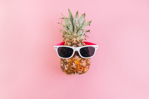 Summer concept. Cute and funny pineapple with sunglasses on pink background.