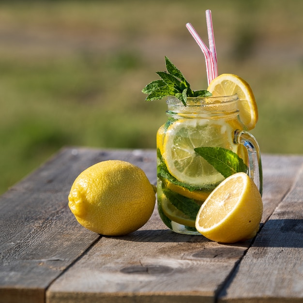 Летняя концепция. Лимонад с лимоном, мятой и льдом в банке, на старый деревянный стол, Открытый.