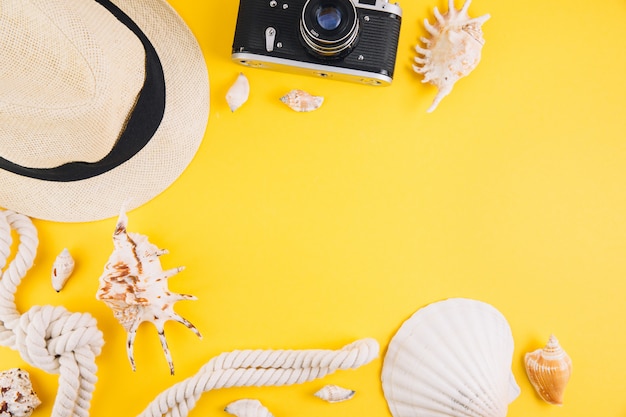 Concetto di estate accessori da viaggio: un cappello di paglia, una macchina fotografica, una corda, conchiglie e occhiali da sole.