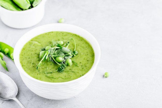 Summer cream soup with green fresh pea shoots closeup