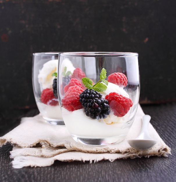 Dessert estivo con frutti di bosco e gelato in bicchieri su uno sfondo nero