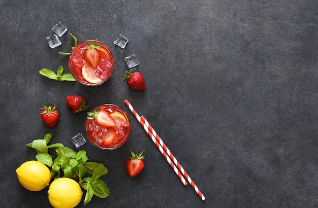 Summer drink. Cold lemonade with strawberries and basil on a concrete background.