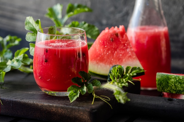 Summer drink Cold watermelon juice with lime and mint on a wooden board Berryfruit smoothie