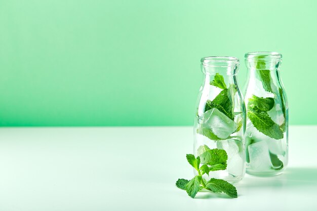 Summer drink, fresh lemonade with mint and ice in glass bottles