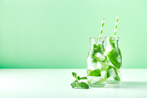 Summer drink, fresh lemonade with mint and ice in glass bottles