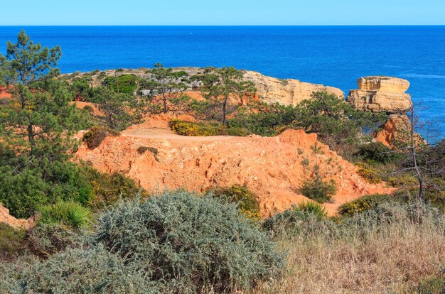 Summer evening Atlantic limestony coast view near beach Praia de Sao Rafael and red clayey earth in front, Albufeira, Algarve, Portugal.