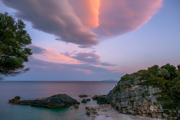 小さな岩のビーチでの夏の夜。多色の雲