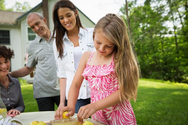 A summer family gathering at a farm A girl slicing and juicing lemons to make lemonade