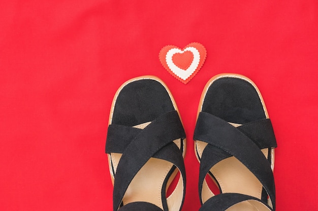 Summer fashion black women's shoes on red fabric with red heart.