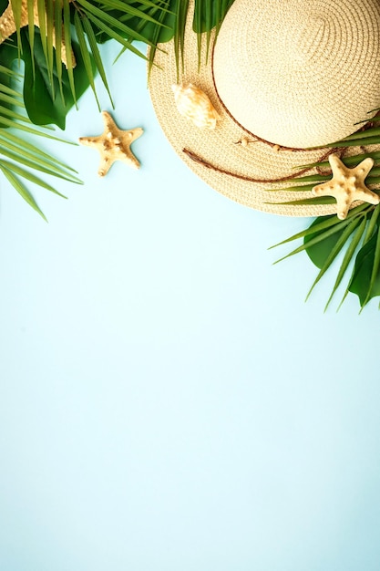 Summer flat lay background Summer vacation and travel concept Palm leaves sea shells and hat on blue background