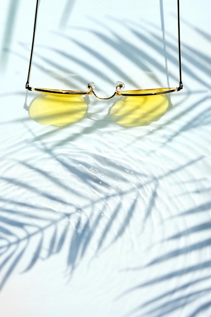 Summer flat lay with yellow sunglasses on water background