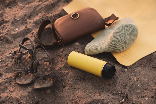 Foto summer flat lay giallo thermos yoga tappeto panama sandali e borsetta sulla spiaggia sulla sabbia