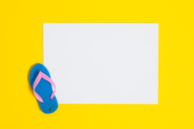 Summer flip flop sandals with a blank white sign on a bright yellow background