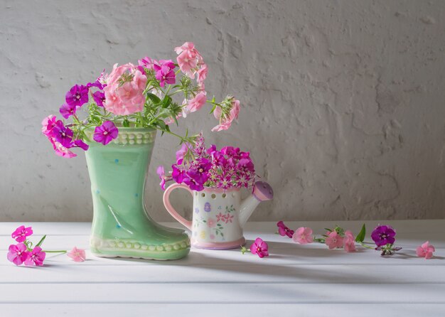 Summer flowers in ceramic boot on white table