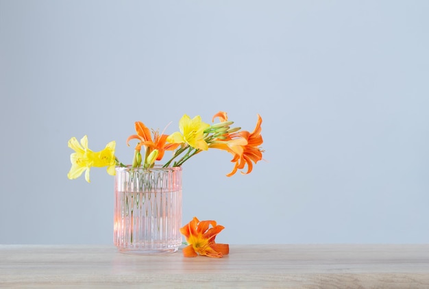 Summer flowers in glass vase on wooden shelf