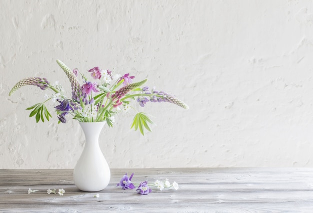 Summer flowers in vase on background white wall