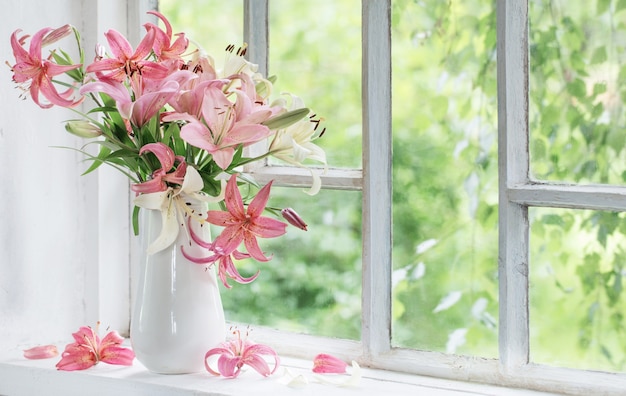 Summer flowers in vase on white windowsill