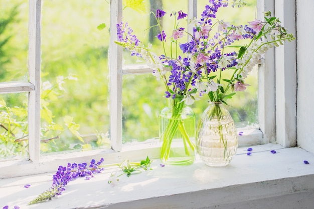 Summer flowers in vase on windowsill in sunlight