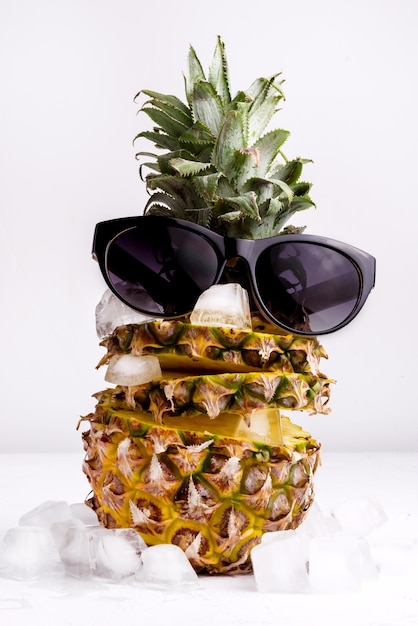 Summer Food Concept vers gesneden ananas met ijsblokje op witte achtergrond Ananas en zonnebril