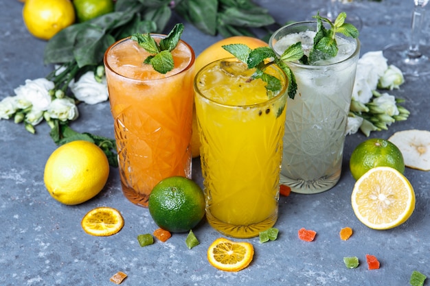 Summer fresh cold drink beverages. Ice Lemonade in the jug and lemons and orange with mint on the table outdoor.