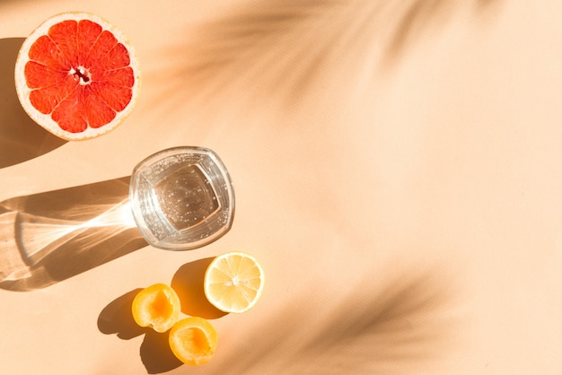 Photo summer fresh food and drinks flat lay with water and slice of orange grapefruit and lemon on beige