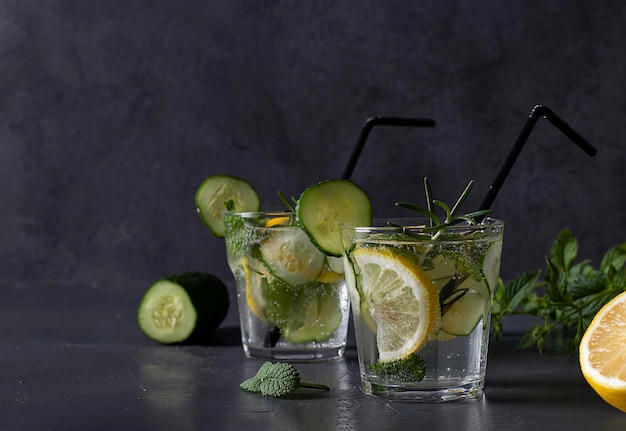 Summer fresh iced drink with mint lemon and cucumber healthy detox mojito cocktail on gray