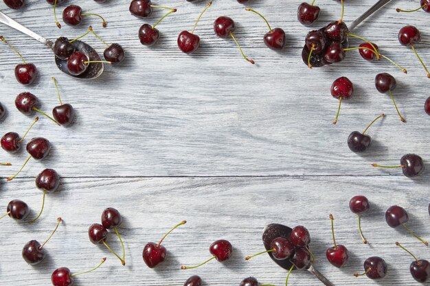 Summer freshly picked cherries pattern with place for text on gray wooden background. Concept of clean organic eating. Flat lay