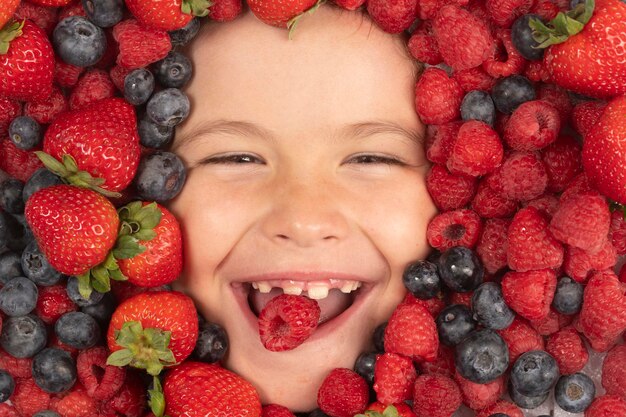 Летняя фруктовая смесь клубники, черники, малины, ежевики, фоновых ягод крупным планом рядом с детьми